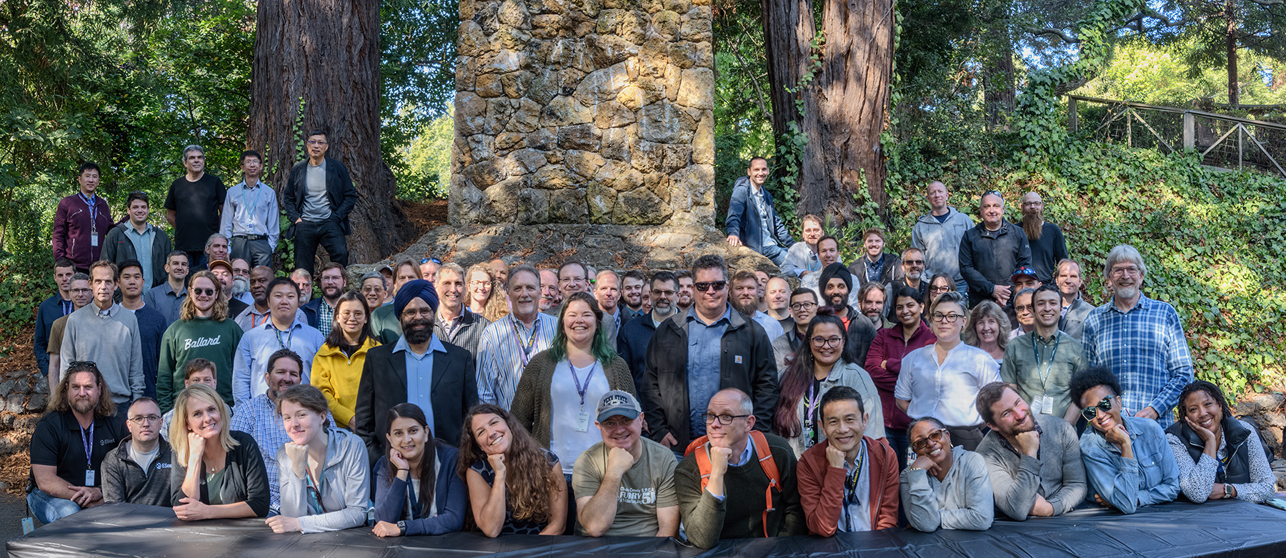 A photo of the ESnet team outside with grass, trees, bushes, and a stone structure behind them