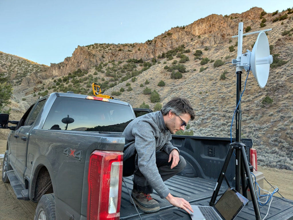 Man in a truck bed looking at a laptop